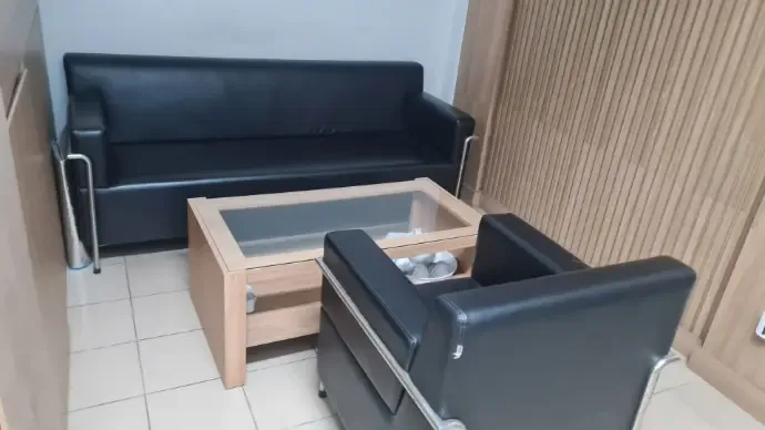 Khu tiếp khách với ghế sofa da đen và bàn kính